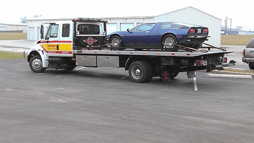 A tow truck with a blue car on the back of it