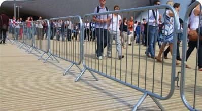 A group of people are walking behind a metal fence.