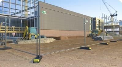 A construction site with a fence and a forklift in front of a building.