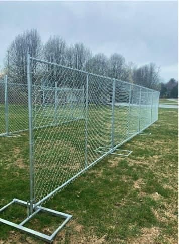 A chain link fence is sitting in the middle of a grassy field.