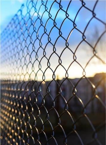 A chain link fence with a blue sky in the background