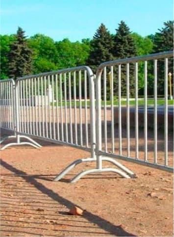 A row of metal barriers sitting on top of a dirt field.