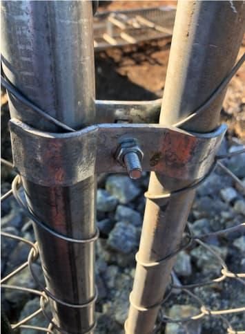 A close up of a metal fence post with a bolt on it.
