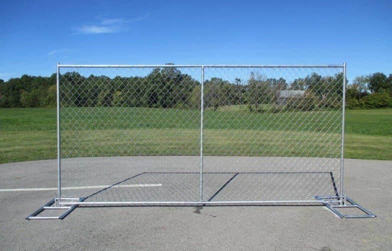 A chain link fence is sitting on the side of a road.