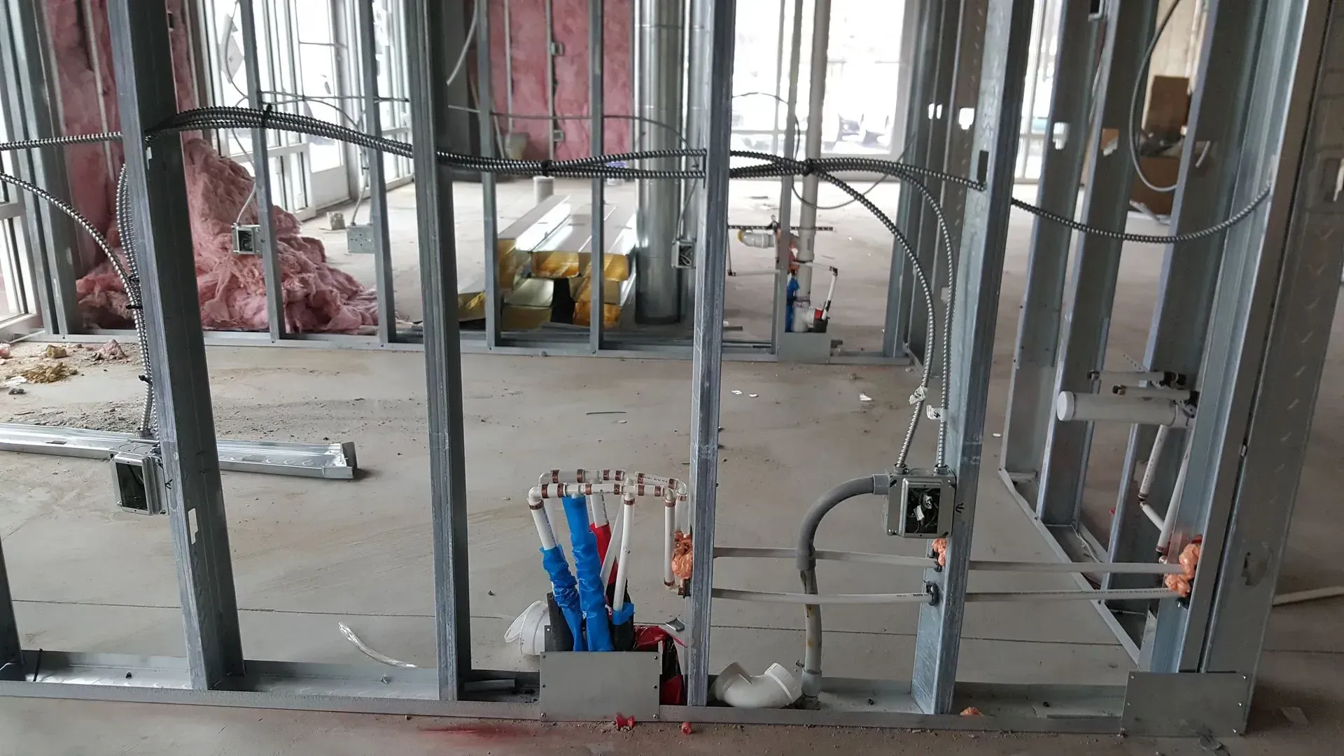 Metal studs frame an interior space under construction, with electrical wiring visible.