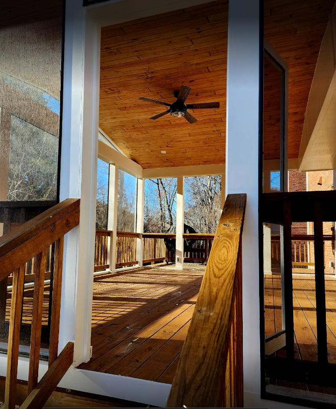 Wooden porch with ceiling fan and sunlight streaming through open doors and windows.