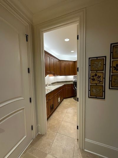Doorway leading to a kitchen with brown cabinets, white counters, and beige floor.