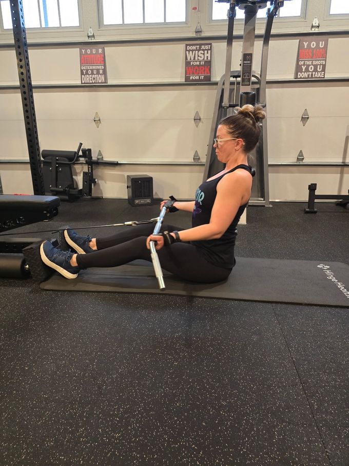 Woman squatting with barbell in a home gym, inside a weight rack.