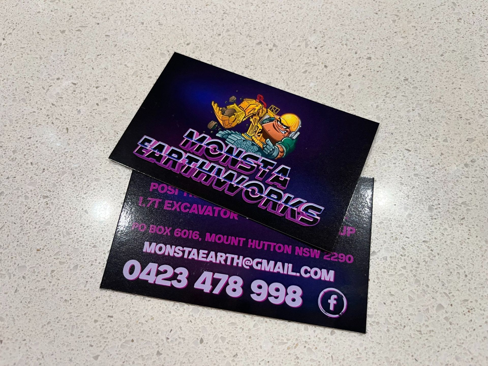 Business cards for Monsta Earthworks. The cards have a logo and contact information on a white surface.