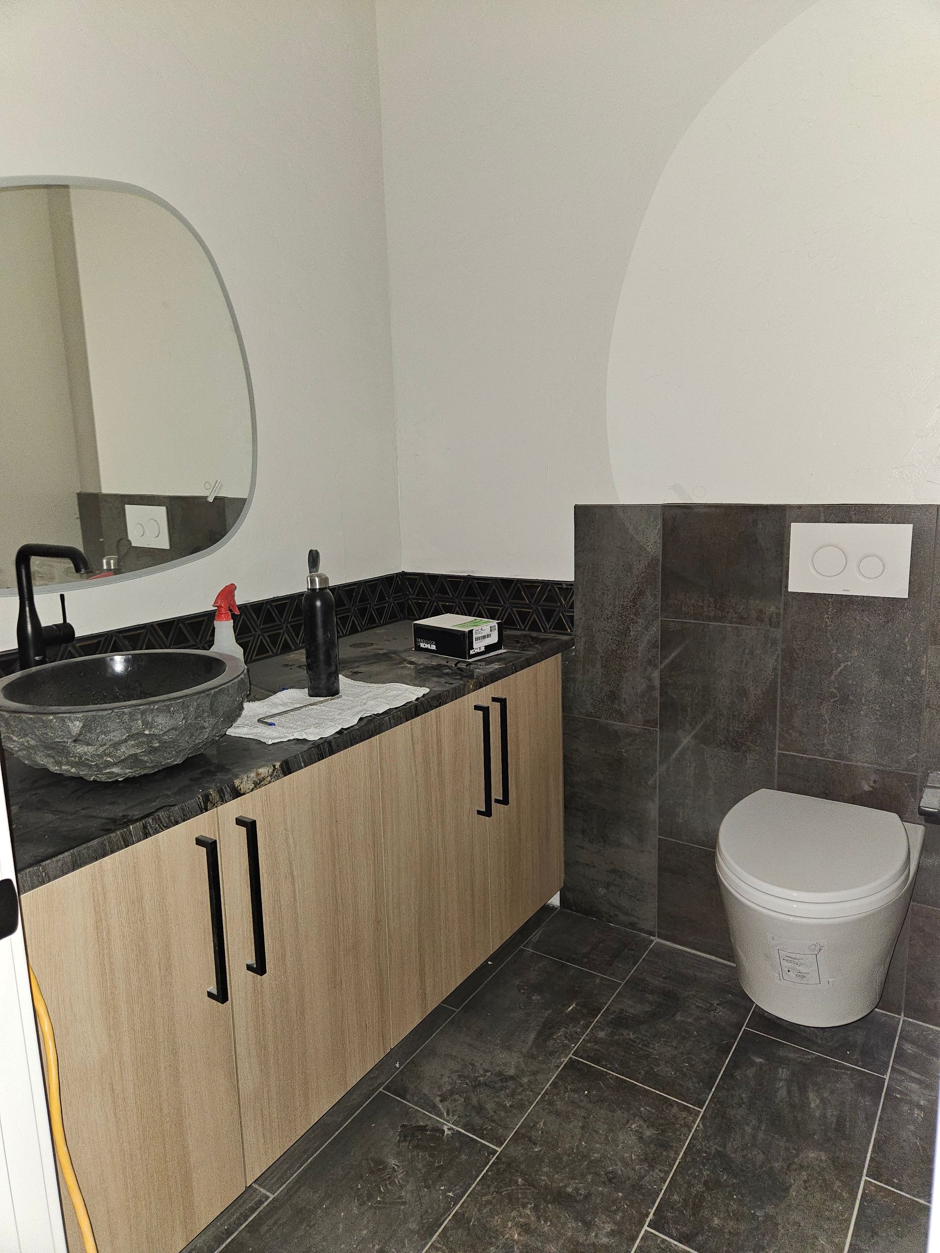 A modern bathroom with a wooden vanity, a stone vessel sink