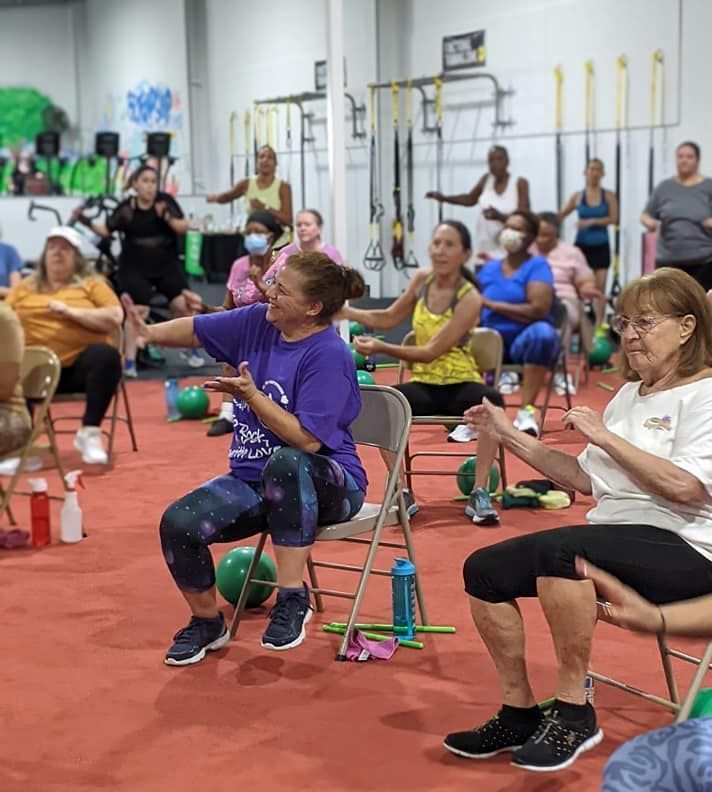 A group of people are sitting in chairs in a gym.
