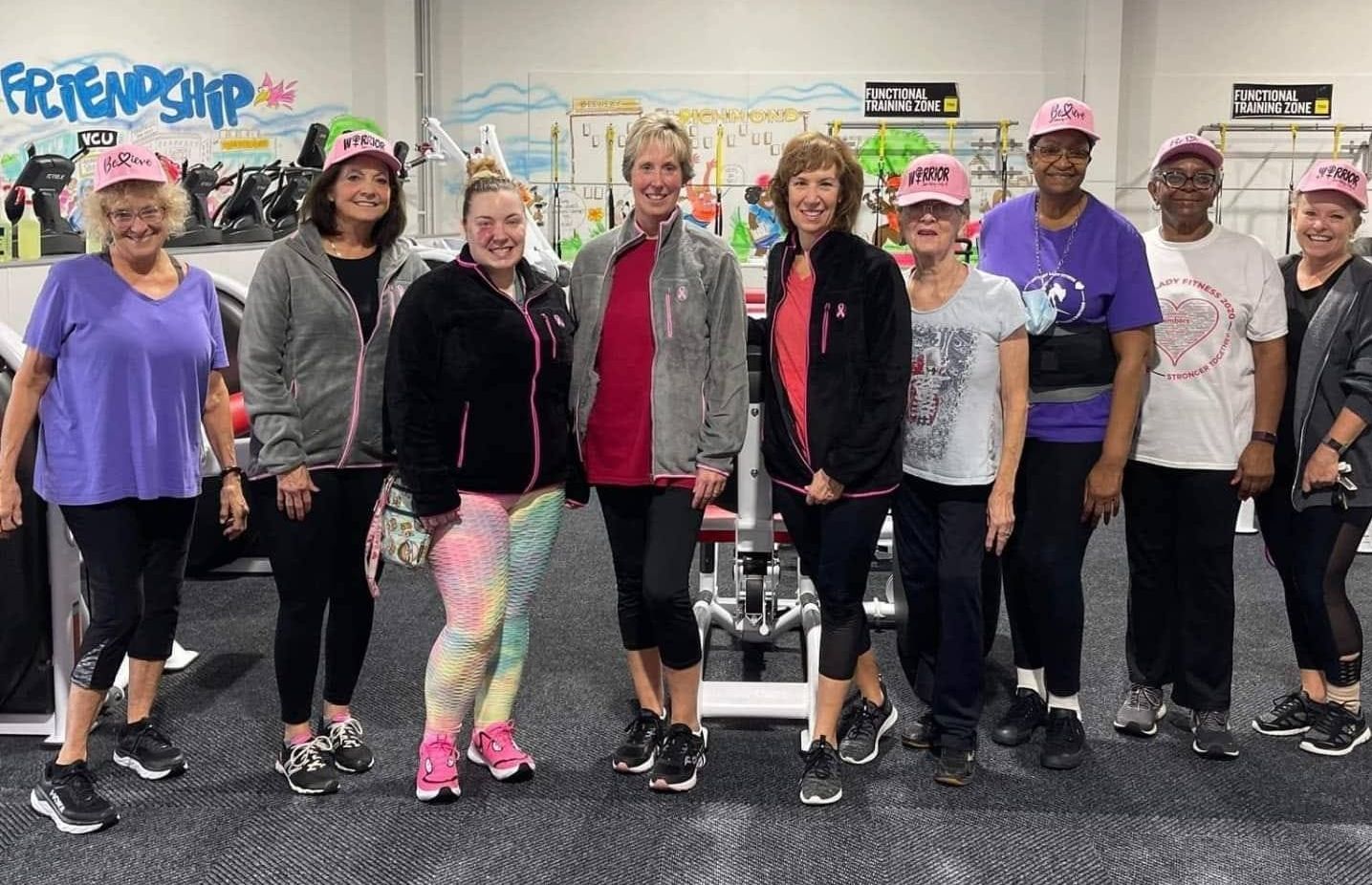 A group of women are posing for a picture in a gym.