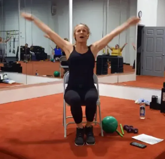 A woman is sitting in a chair with her arms outstretched