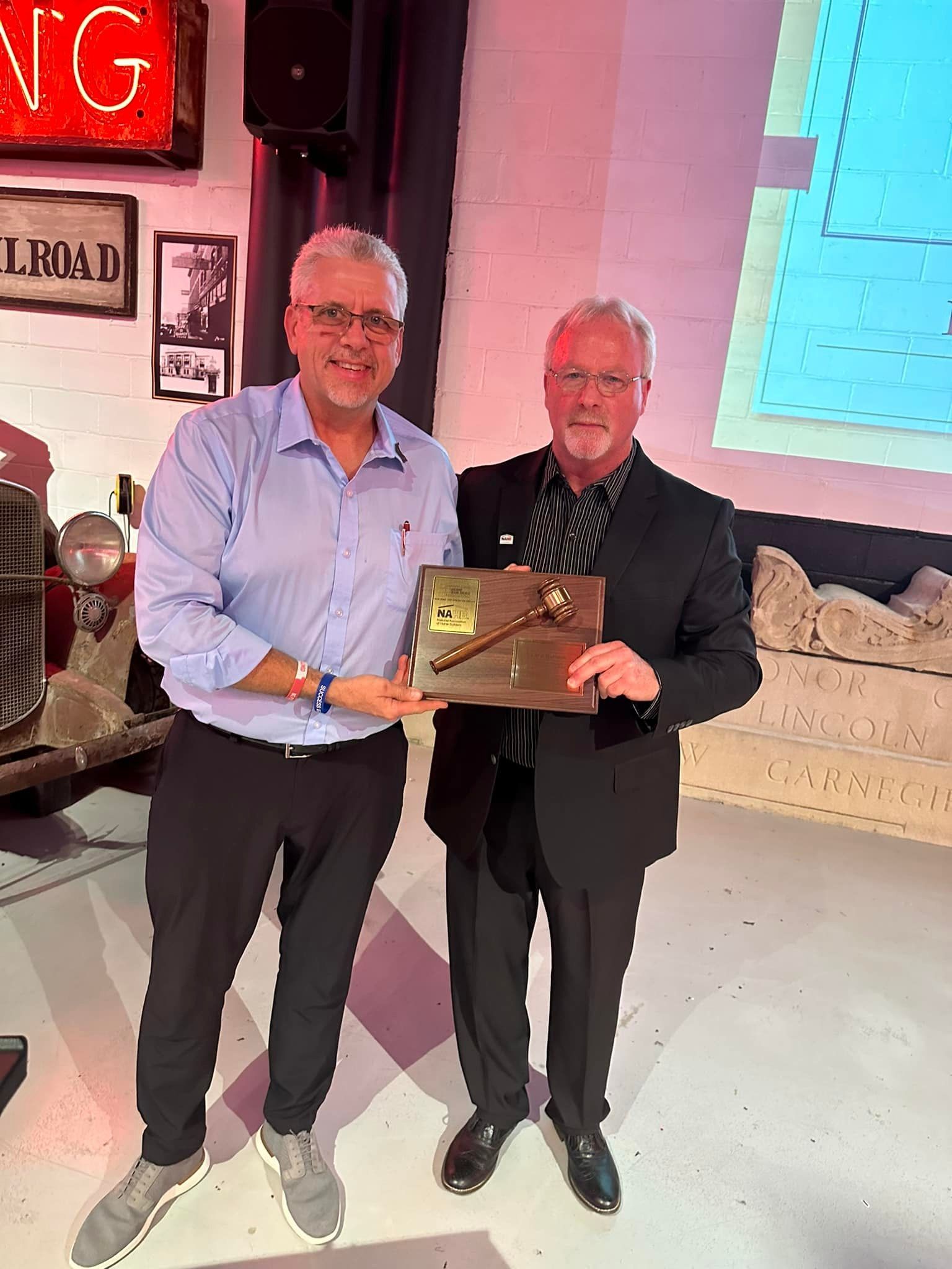 Two men are standing next to each other holding a plaque.