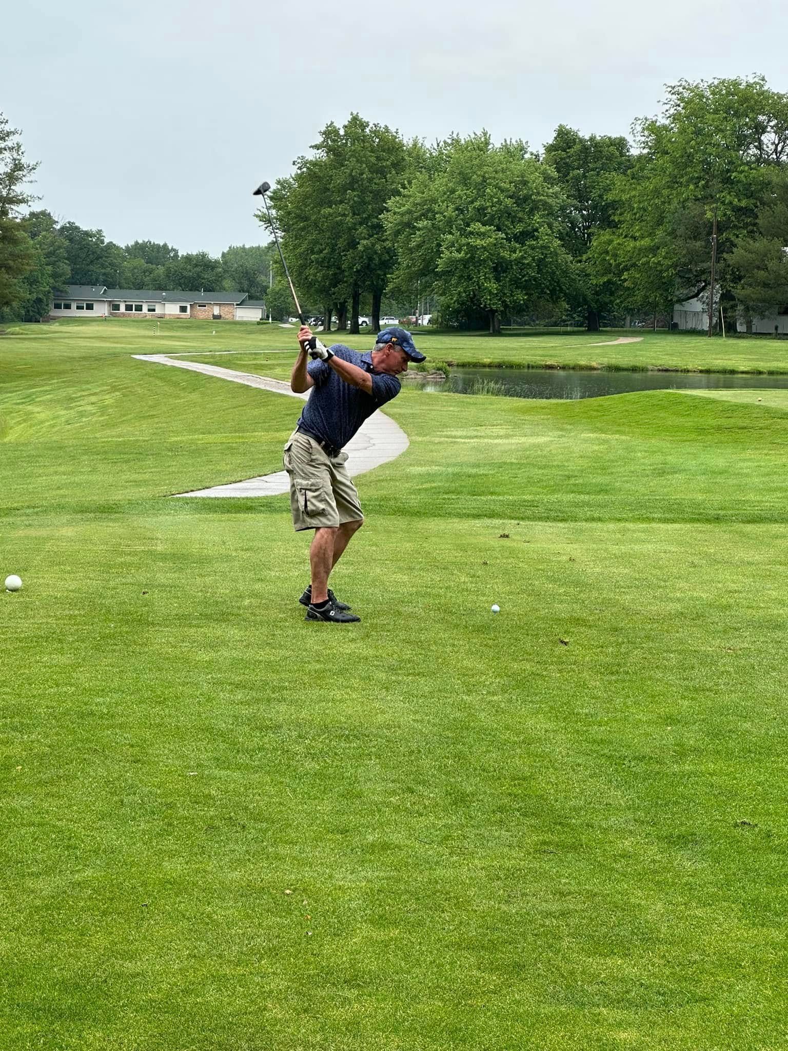 A man is swinging a golf club on a golf course.