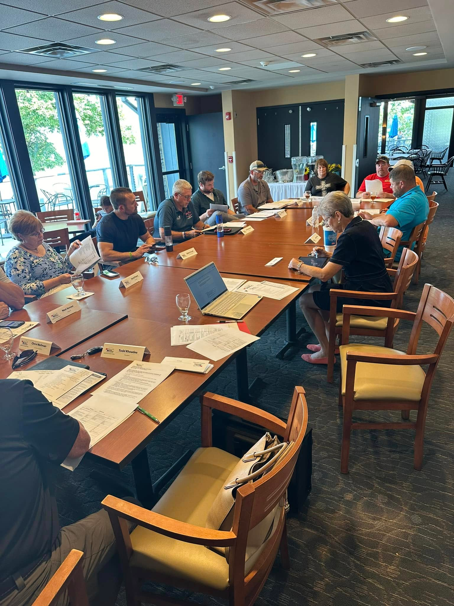 A group of people are sitting around a long table in a room.