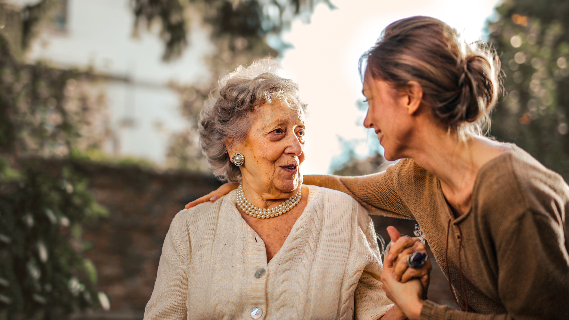 Two women chatting outdoors, smiling at each other in a garden setting.