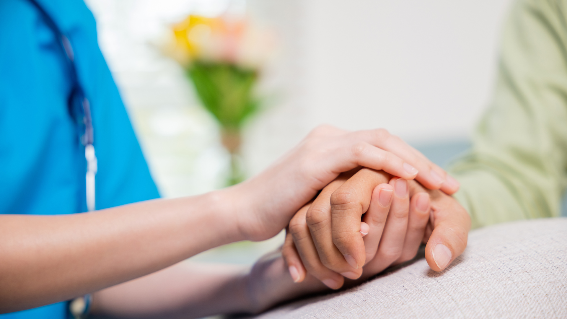 Healthcare worker holding a patient’s hand in a supportive, caring gesture