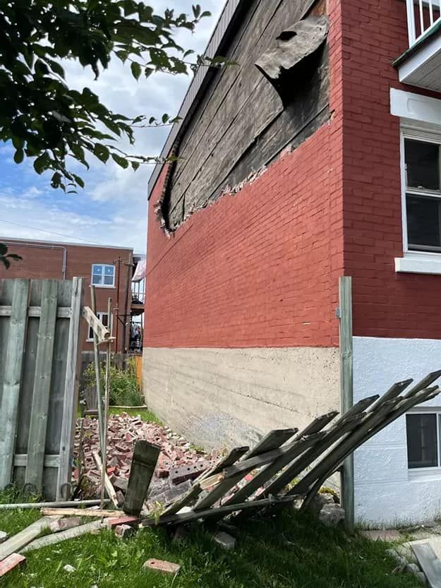 Un bâtiment en briques rouges avec une clôture en bois devant.