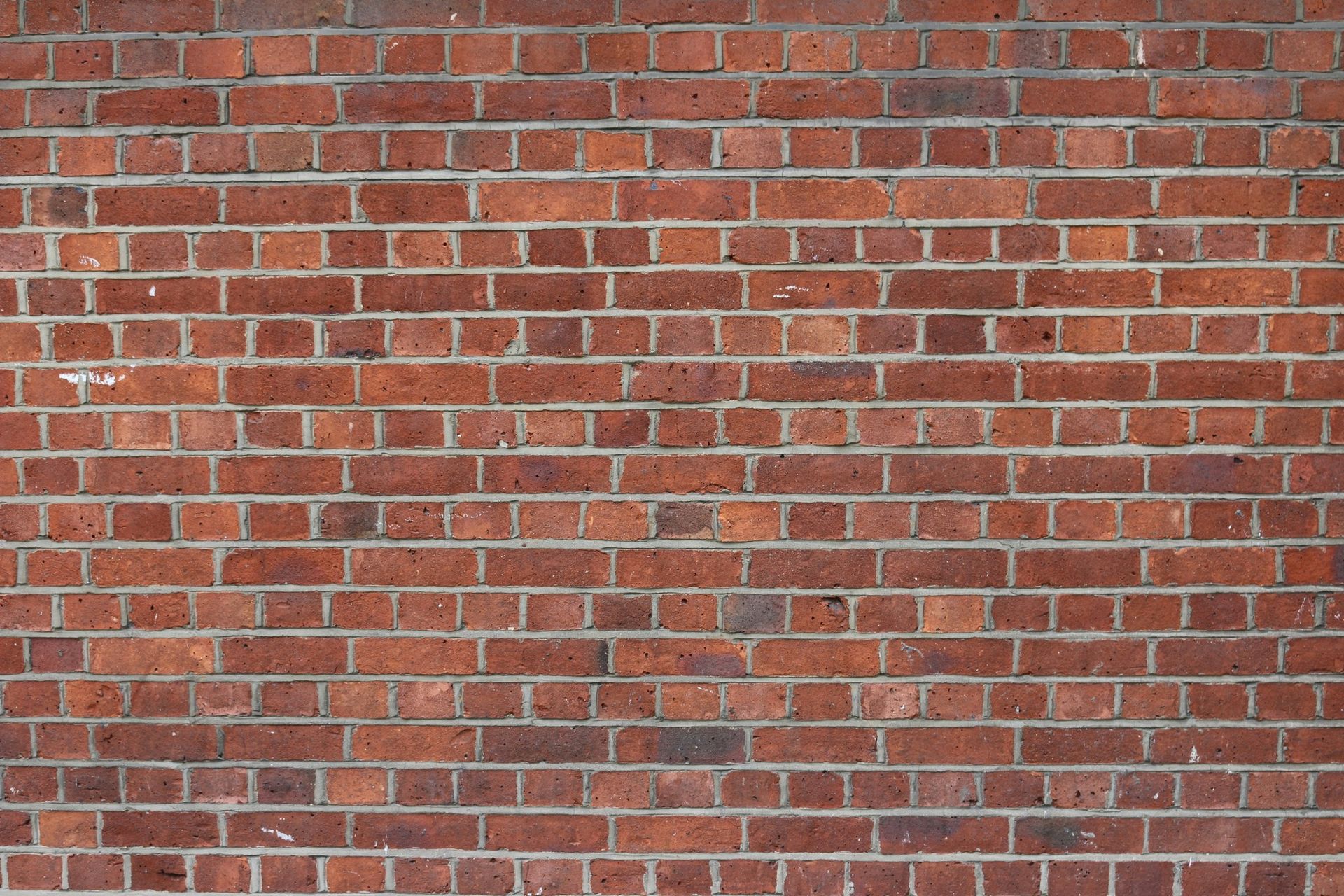 Mur en briques rouges avec mortier gris et légères taches blanches dues à l'érosion