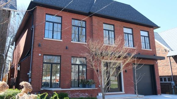 Une grande maison en briques rouges avec des fenêtres noires et un toit noir.