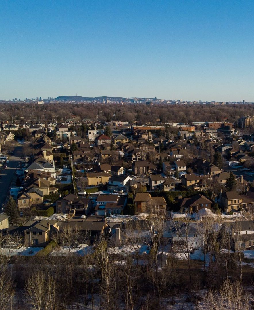Une vue aérienne d'une petite ville entourée d'arbres par une journée ensoleillée.