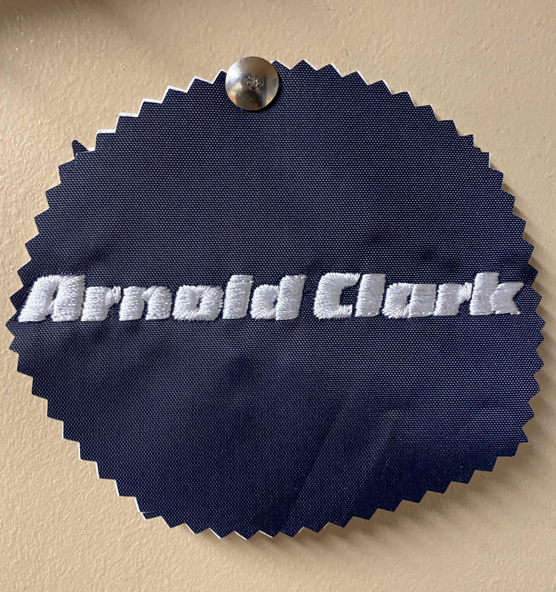 A navy blue fabric swatch with the embroidered name 