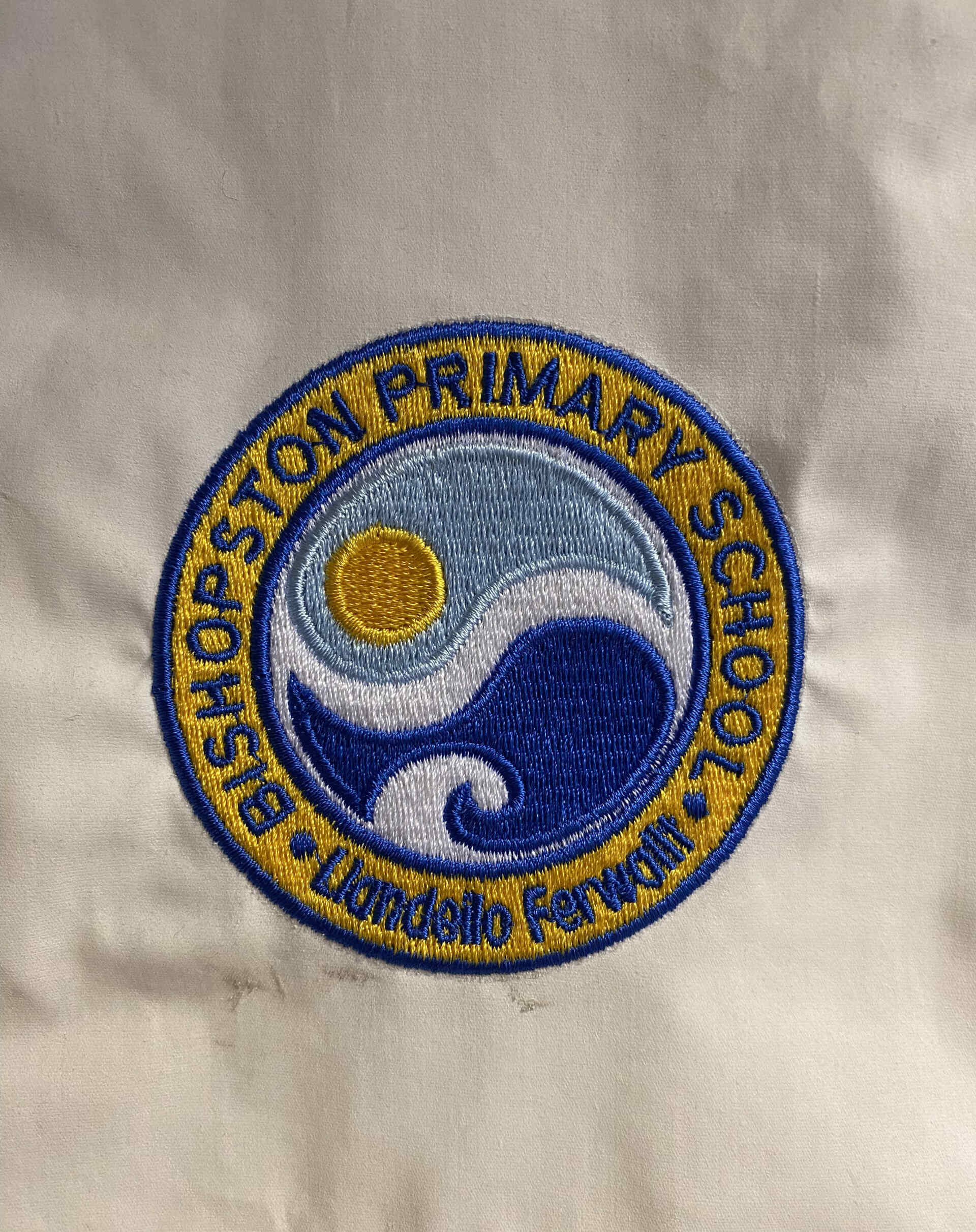 Bishopston Primary School embroidered emblem: featuring a sun, waves, and text 