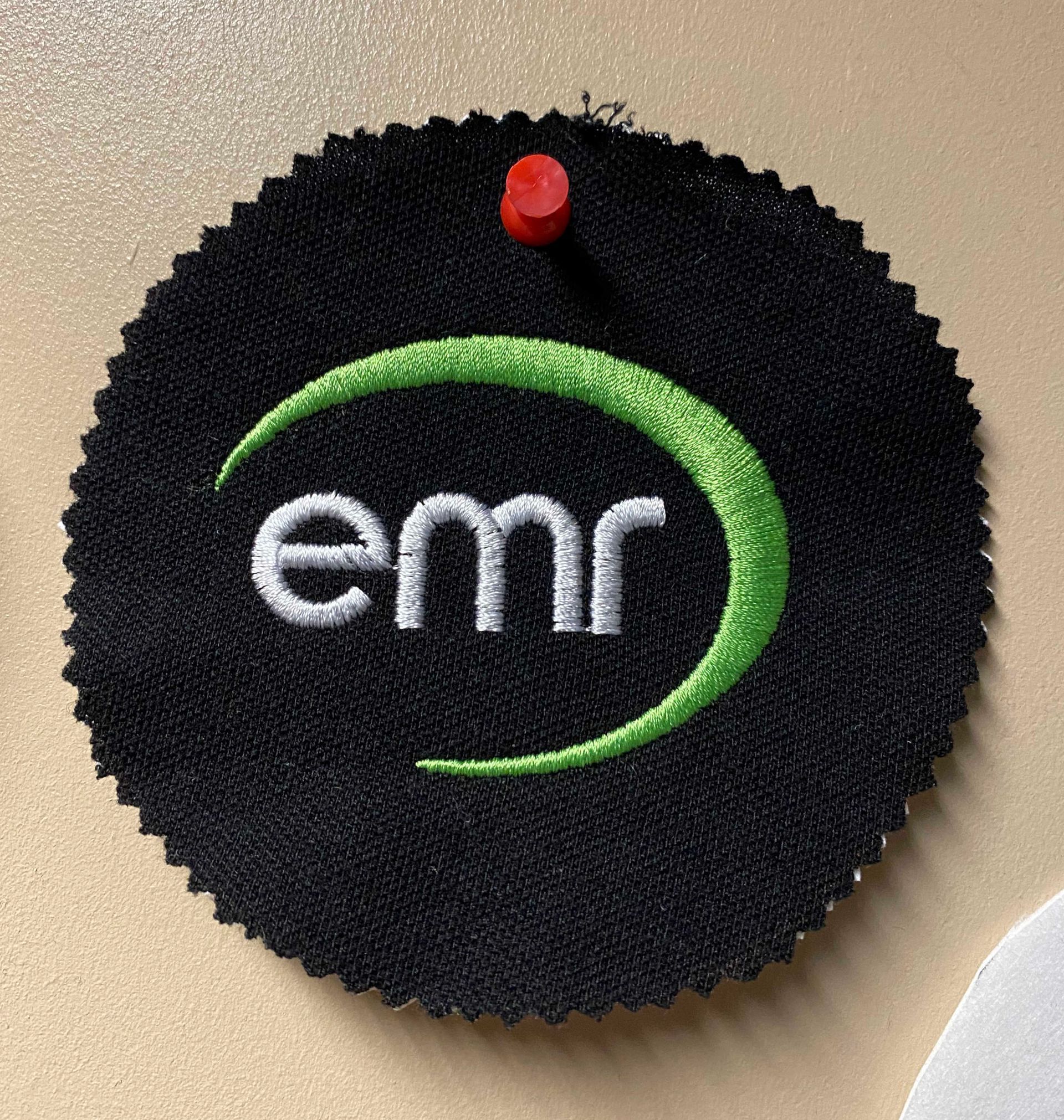 A black fabric circle with a green and white embroidered 