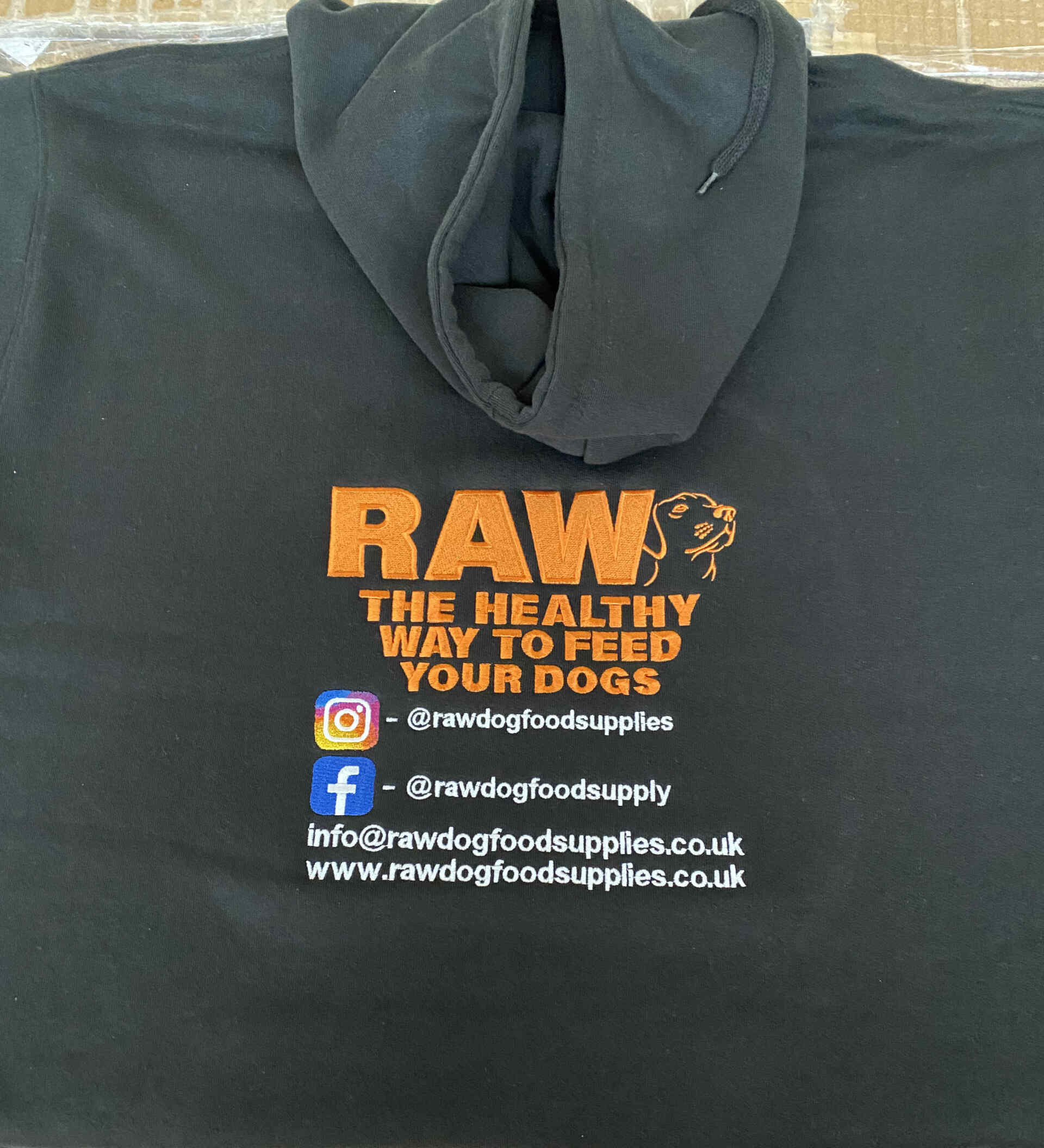 Black hoodie with embroidered orange text: 