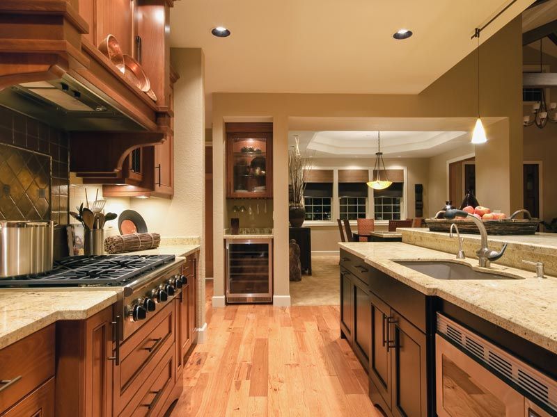 Modern kitchen with wooden cabinets, stainless appliances, and a central island under warm lighting