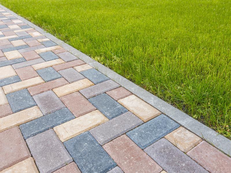 Colorful brick walkway beside a green grass lawn