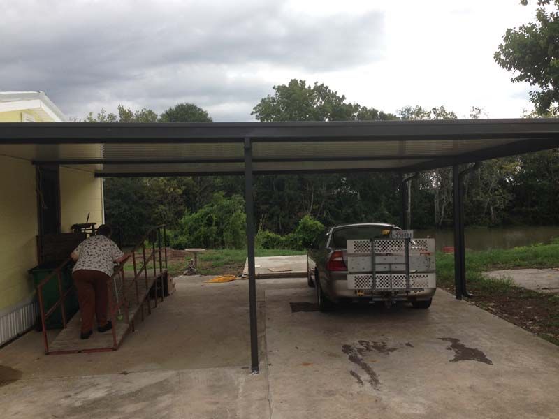Covered driveway with a parked truck and a person bending over a red ramp on the left