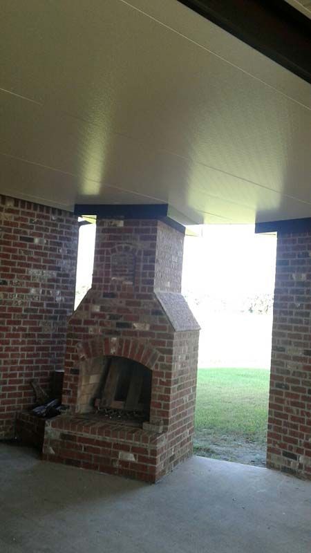 Brick outdoor fireplace under a covered patio, opening to a grassy yard.