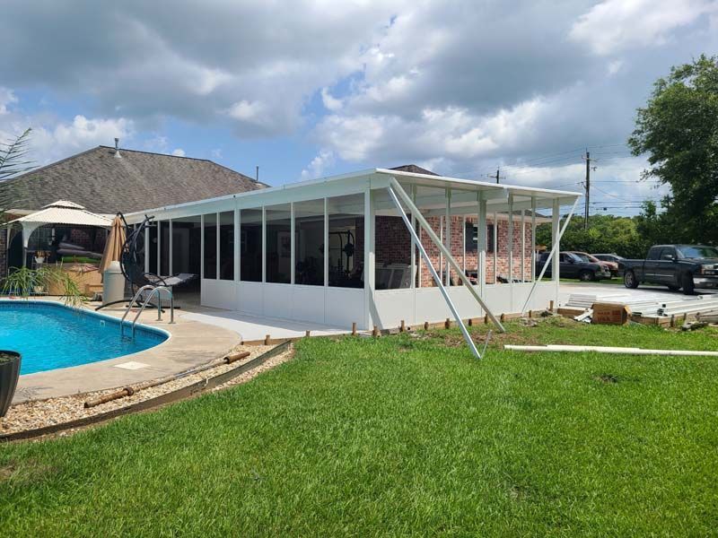 Backyard screened patio enclosure beside a pool and lawn under cloudy skies