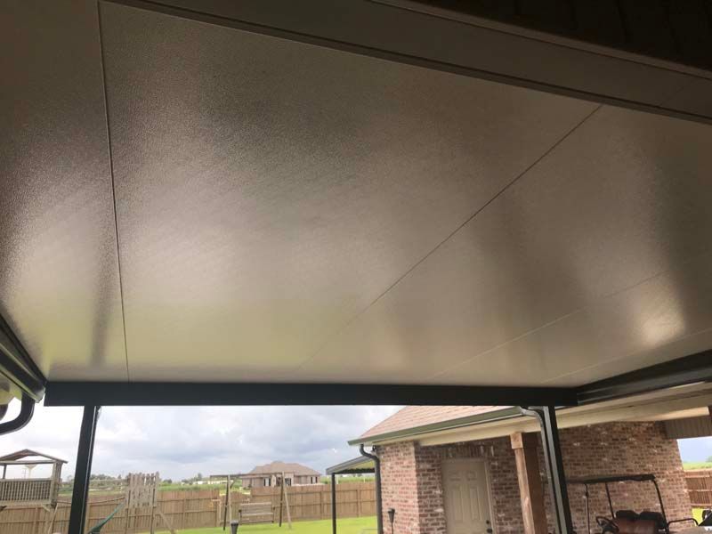 Covered patio ceiling overlooking a fenced backyard and brick house exterior