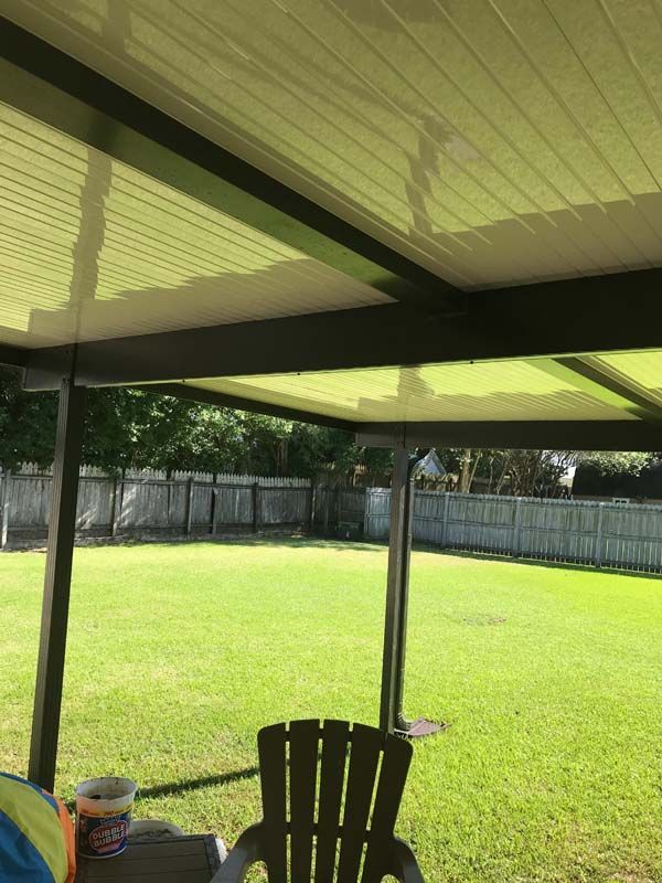 Shaded backyard patio overlooking a bright green lawn and fenced yard.