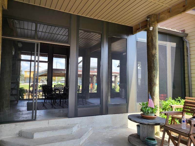Covered patio with glass doors, steps, and outdoor table with flowers next to chairs