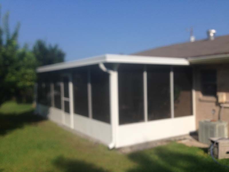 Screened porch attached to a house with white trim and dark mesh panels