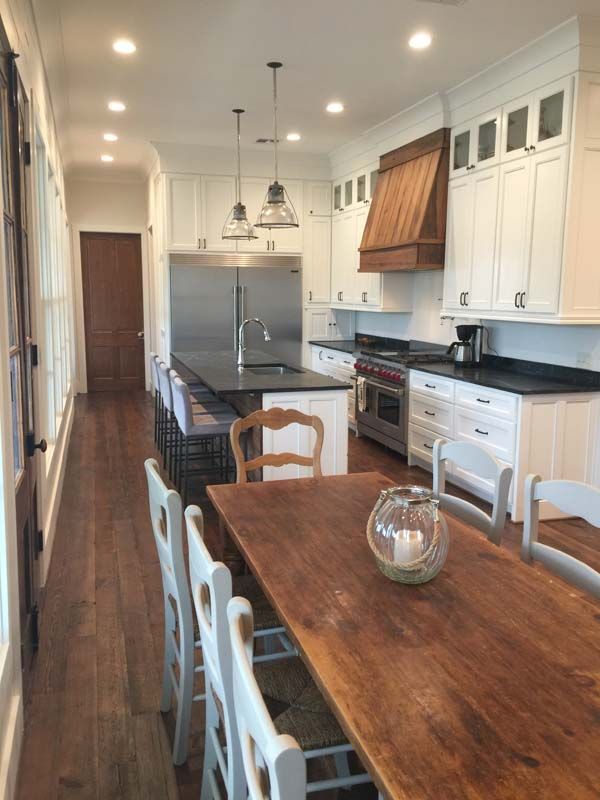 Bright kitchen with wood dining table, white cabinets, stainless appliances, and pendant lights