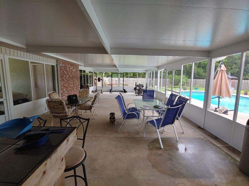 Covered patio with lounge chairs and a pool view beside a brick house