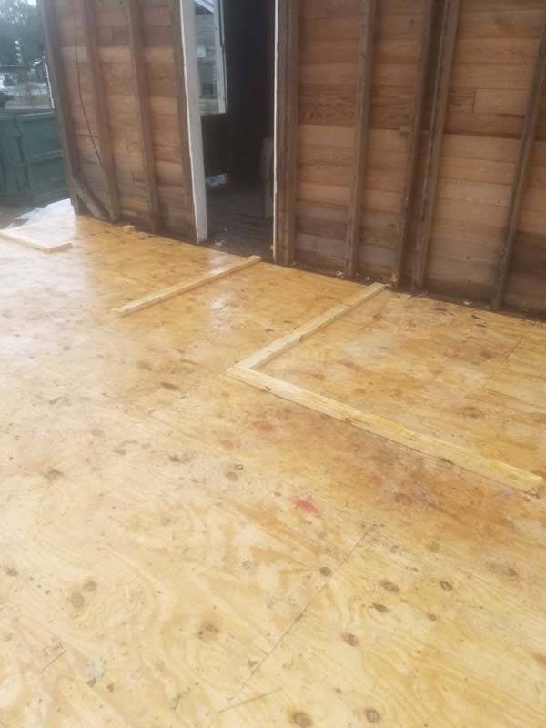 Partially renovated wooden interior with plywood floor and exposed wall framing
