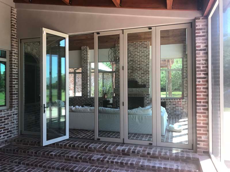 Open glass doors to a brick patio and screened porch with a bed inside.