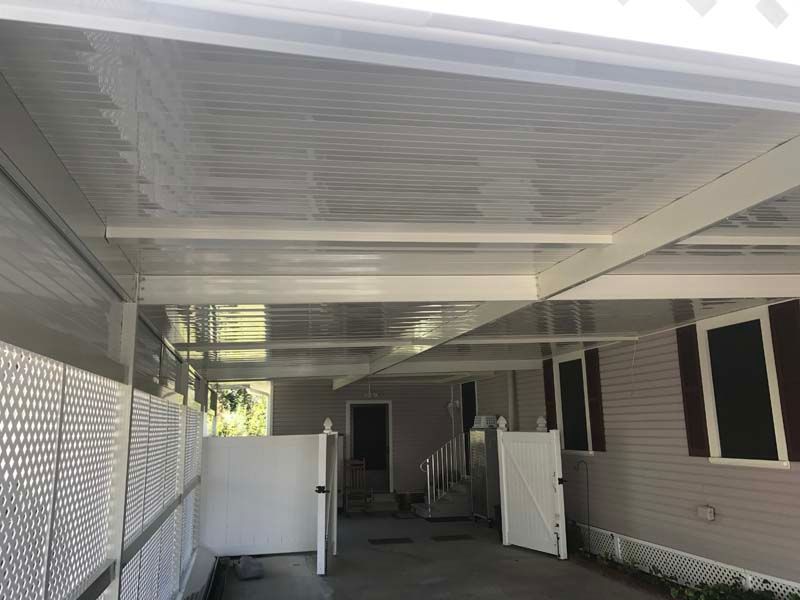 Covered patio with white lattice walls, open gates, and gray house siding