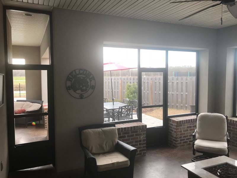 Indoor patio lounge with wicker chairs, brick half-walls, and large windows overlooking a courtyard