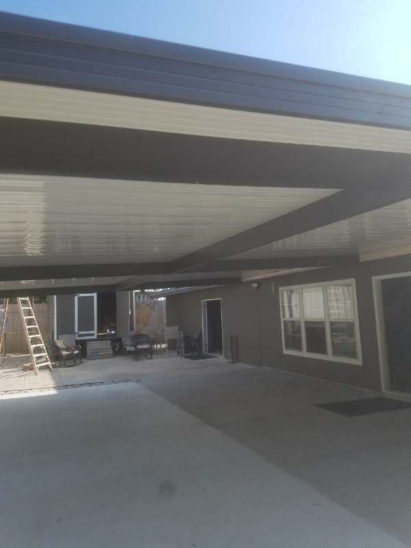 Covered outdoor patio beside a house, with a ladder and windows in view.