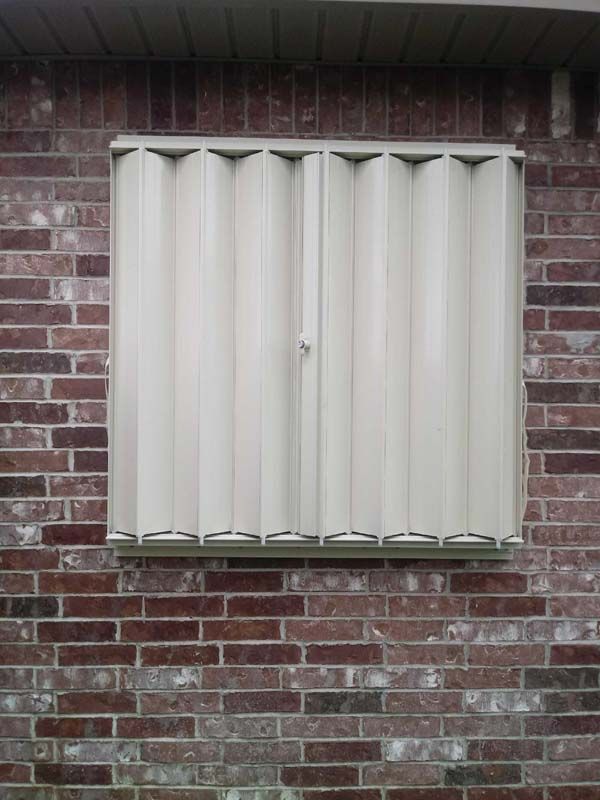 Closed beige window blinds on a brick wall