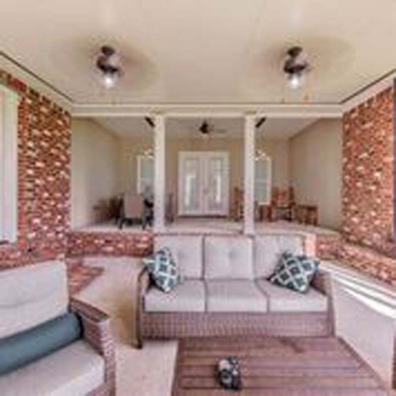 Cozy sunroom with brick accents, beige sofa, and a matching armchair under ceiling lights.