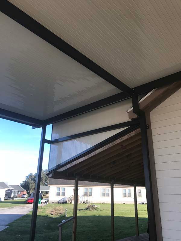 Covered porch with black support posts and white ceiling, overlooking a grassy yard and houses beyond