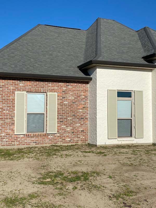 Brick house exterior with beige shutters and gray roof
